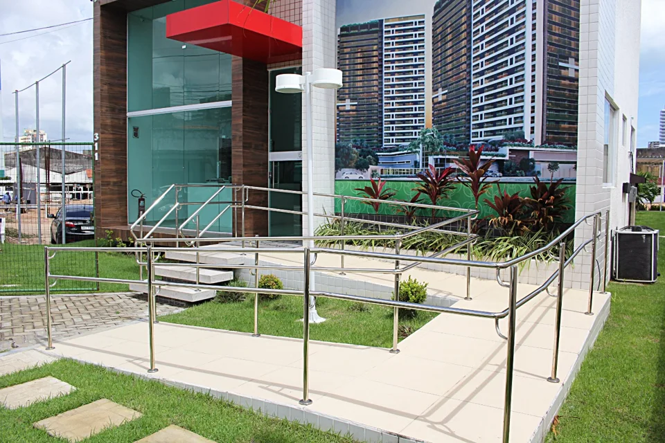 Corrimãos acompanhando rampa e escada de acesso externo na obra identificada como Construtora Acopi