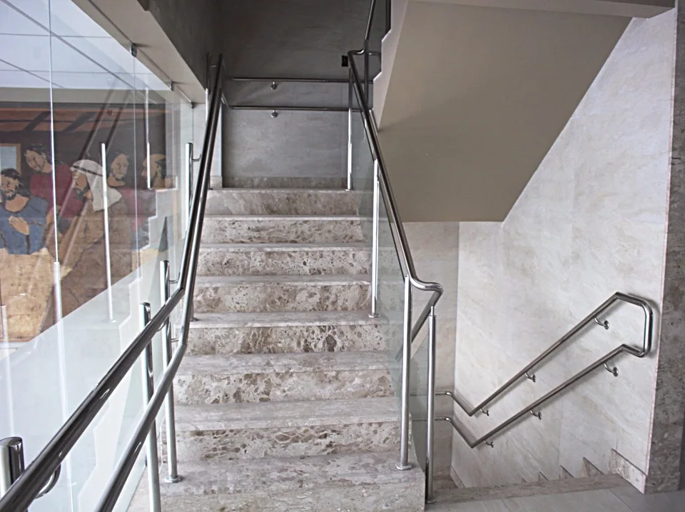 Escada de pedra com corrimãos tubulares e fechamento lateral de vidro na matriz Pague Menos